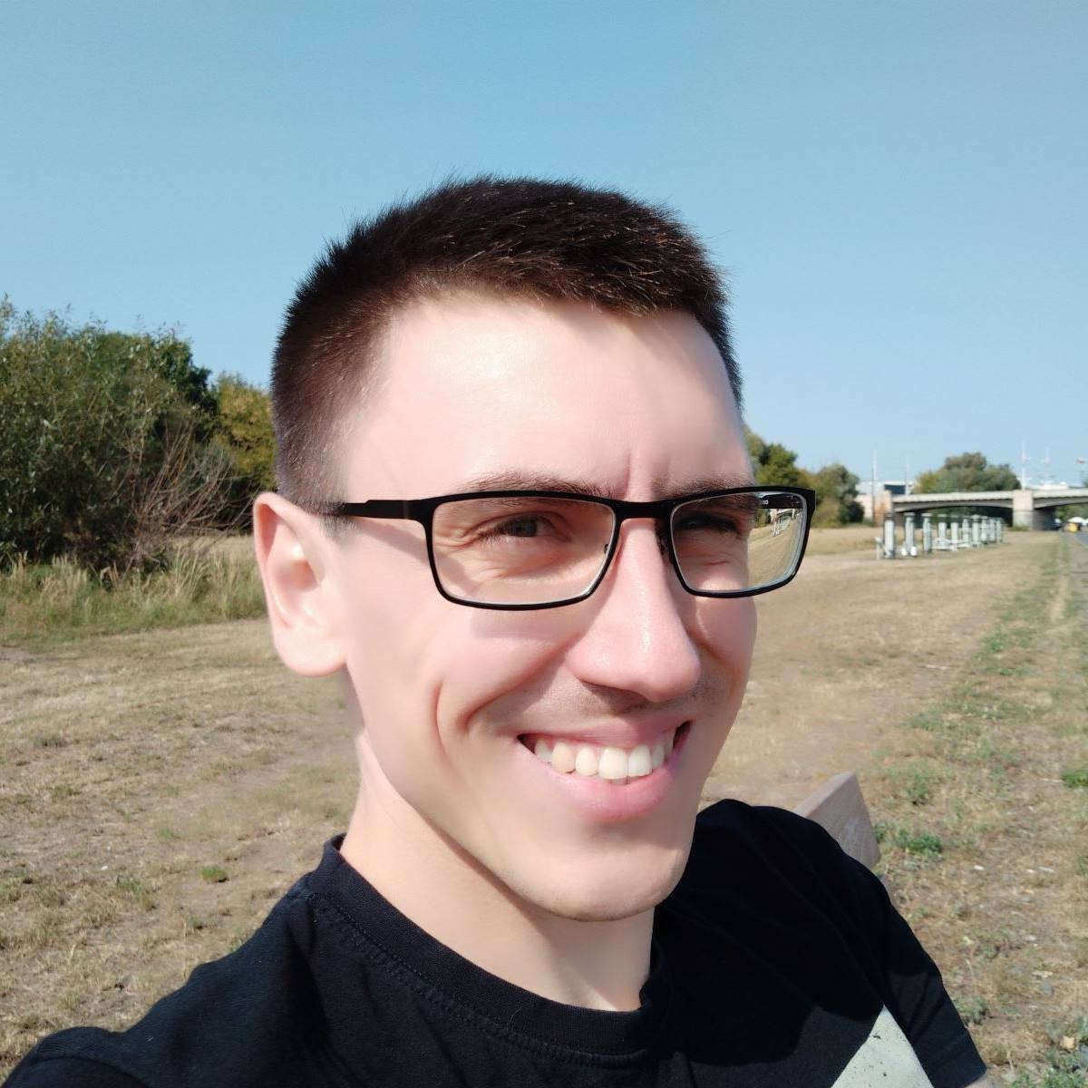 Robert Wierzchowski uśmiechnięty na zdjęciu plenerowym